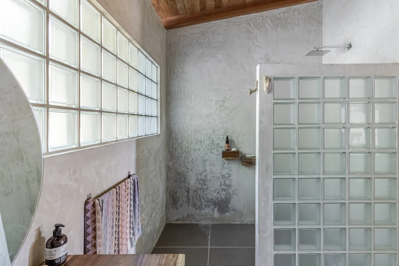 Walk-in shower with concrete walls and a glass-block screen