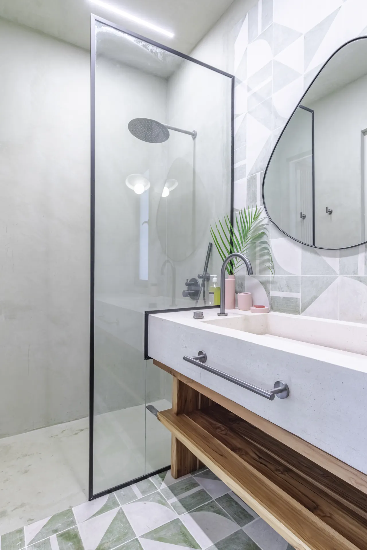 Glass-enclosed shower beside a bathroom vanity and patterned tiles
