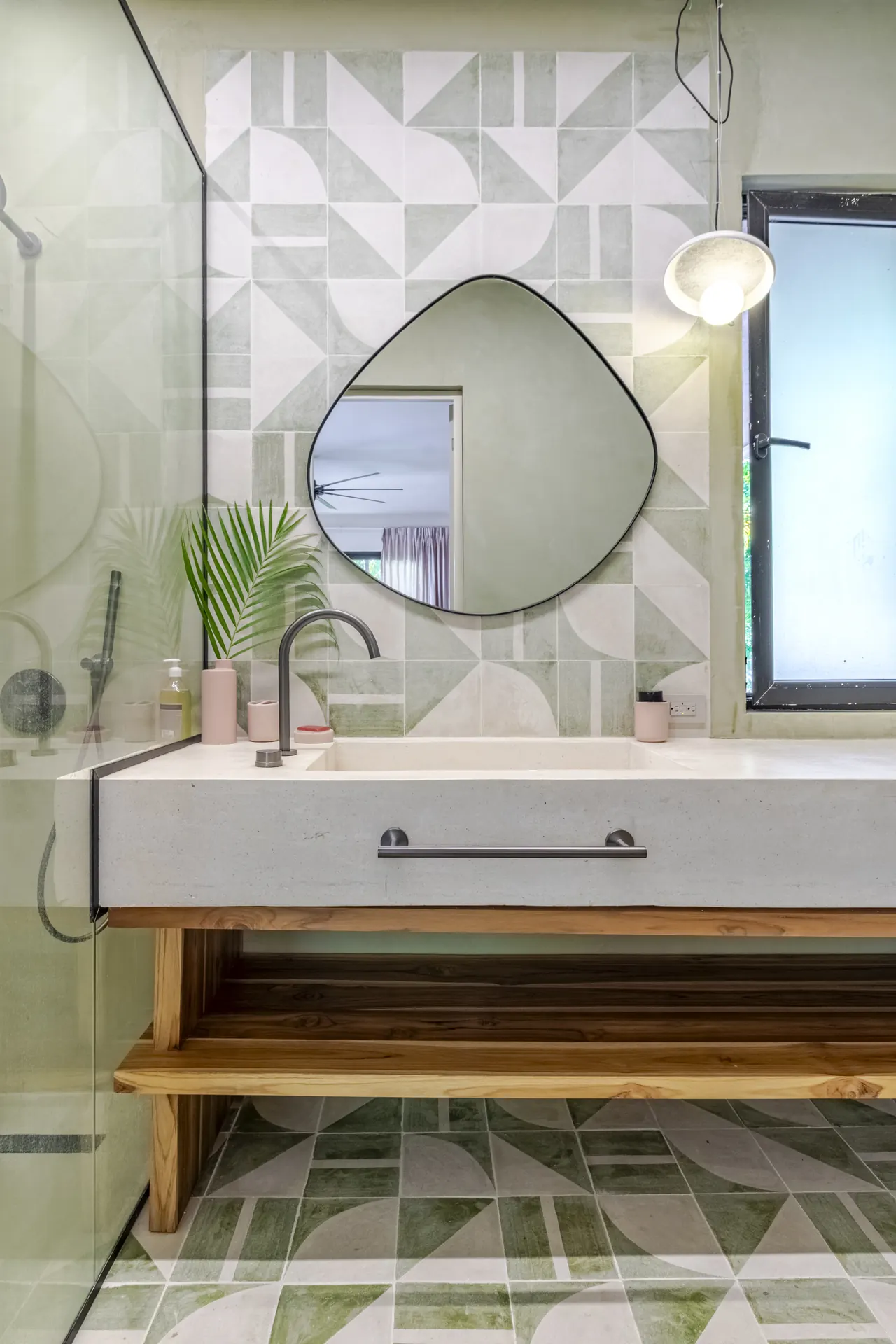 Bathroom vanity with a round mirror, geometric tiles and pendant light