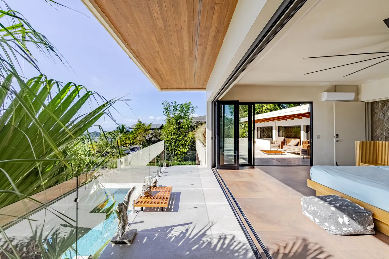 Open king bedroom and upper terrace with a glass railing and ocean outlook