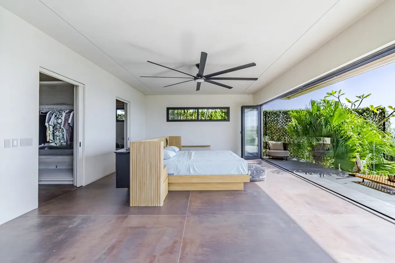 King bedroom with open glass doors facing the planted upper terrace
