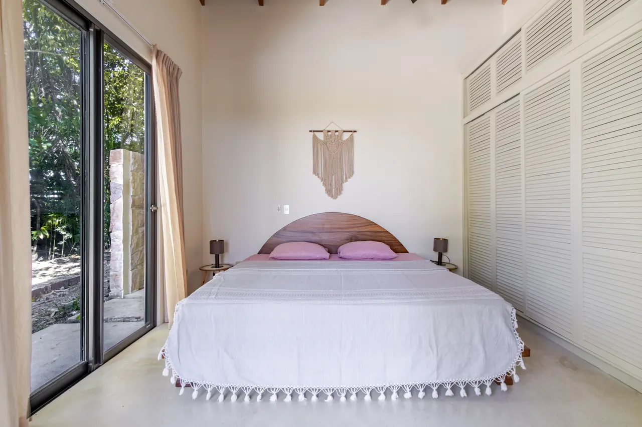 King bedroom with white cabinetry and doors opening to the garden