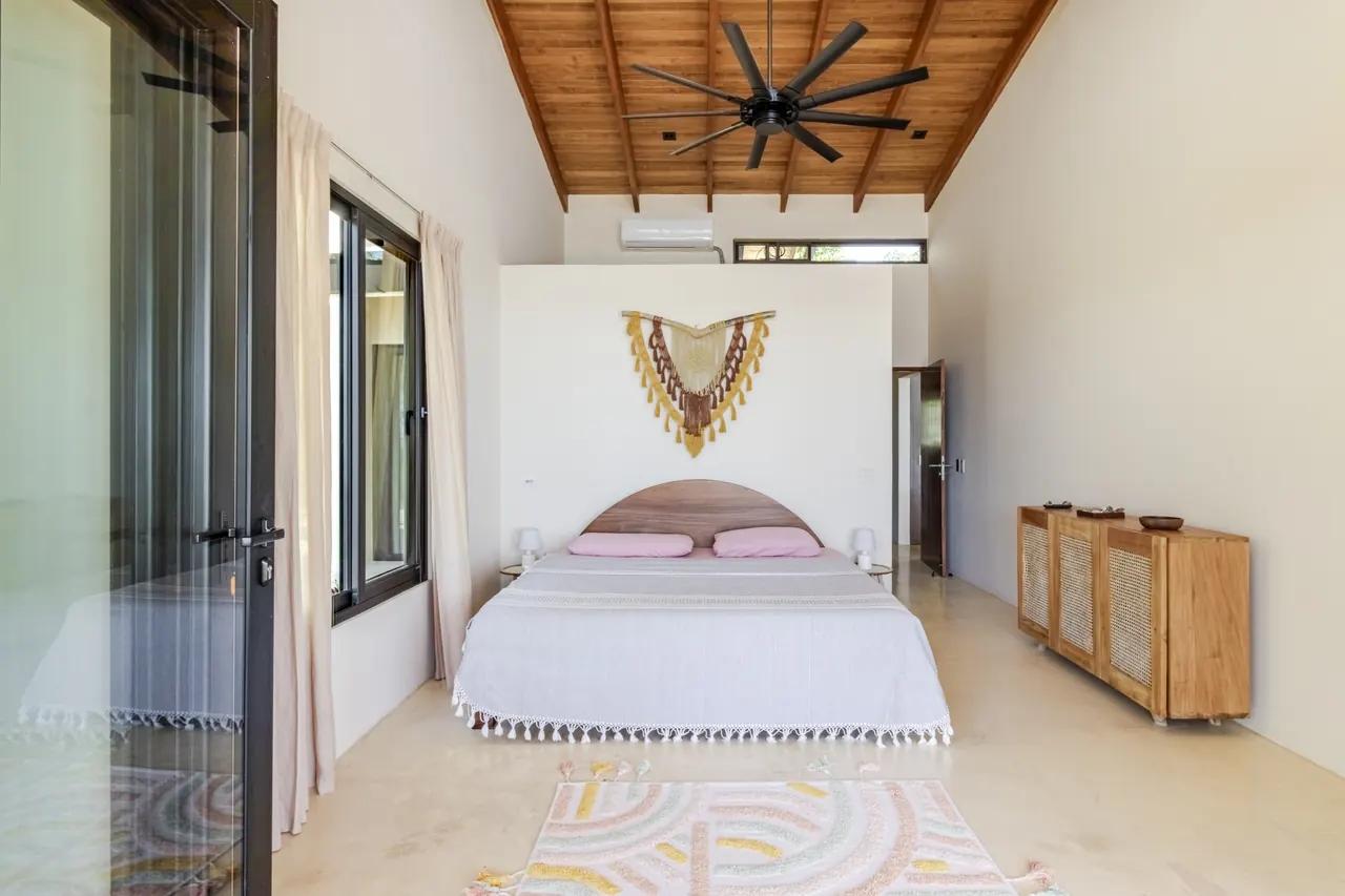 King bedroom beneath a timber ceiling with sliding glass doors