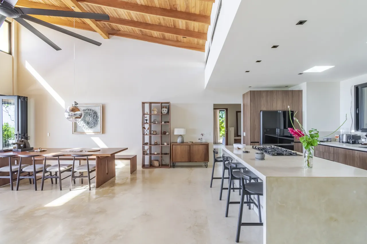 Dining table and kitchen island beneath the villa’s timber roof