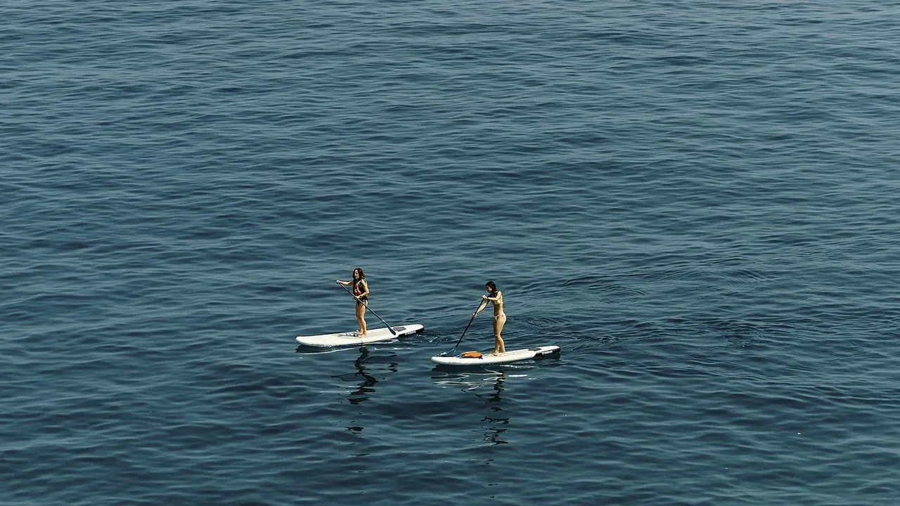 Two paddleboarders on blue water off Playa de Calahonda, Spain.