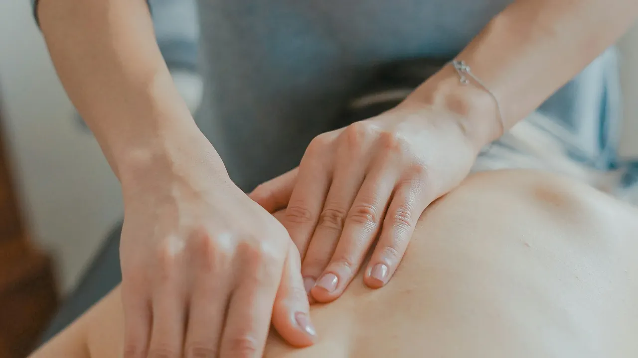 Close-up of a massage therapist’s hands applying pressure to a client’s back.
