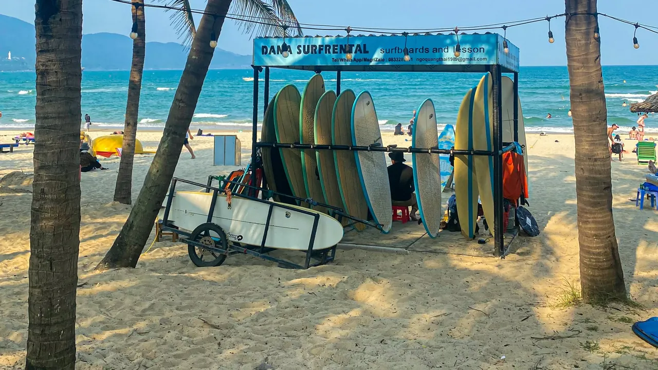 A rack of surfboards under palm trees at a beach in Da Nang, Vietnam.