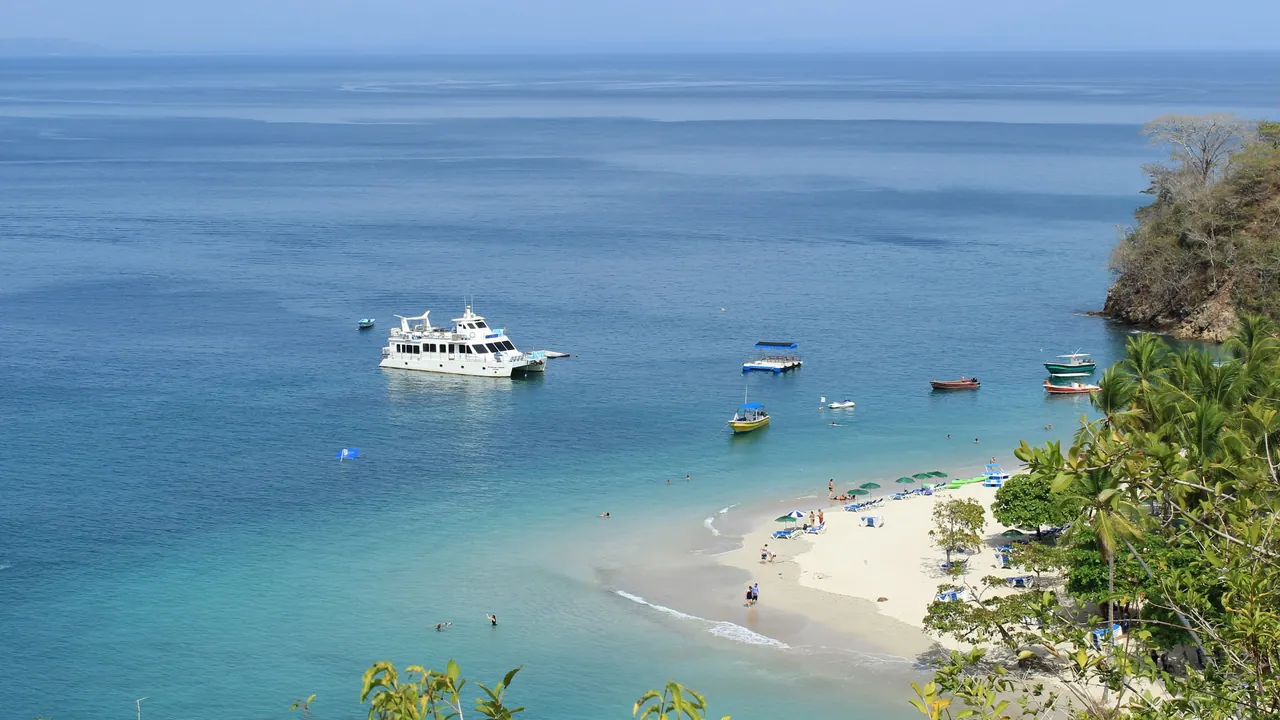 White beach, anchored boats, and blue water seen from Isla Tortuga in Costa Rica.