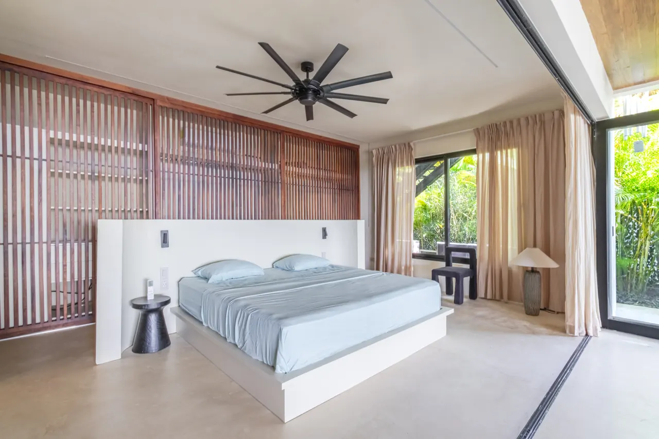 King bedroom with floor-to-ceiling curtains and a timber feature wall
