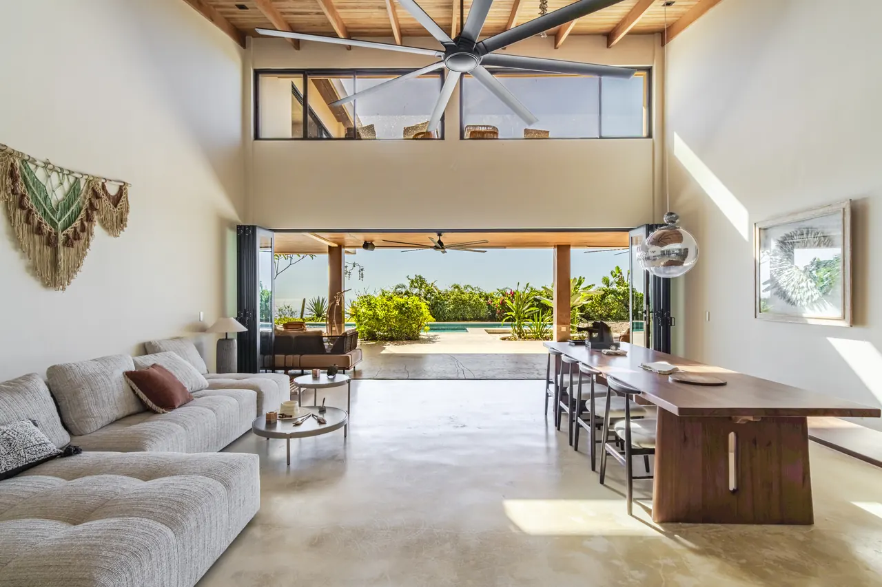 Double-height living room opening onto a shaded tropical terrace