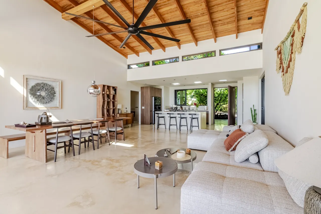 Living and dining room with a sofa, long table and vaulted timber ceiling