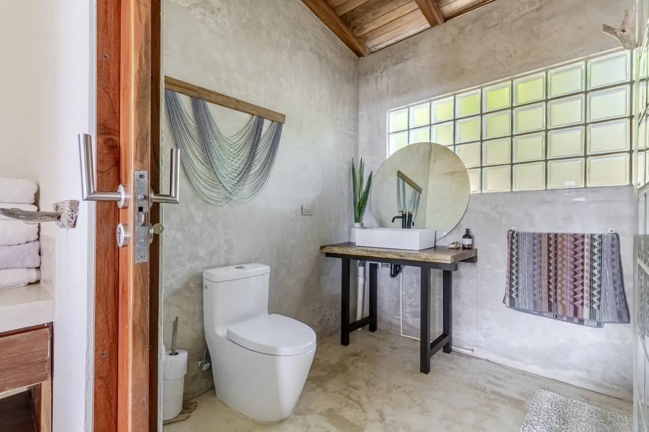 Powder room with concrete walls, round mirror and timber ceiling