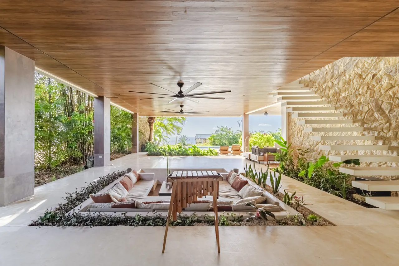 Terrace lounge and small dining table facing the tropical landscape