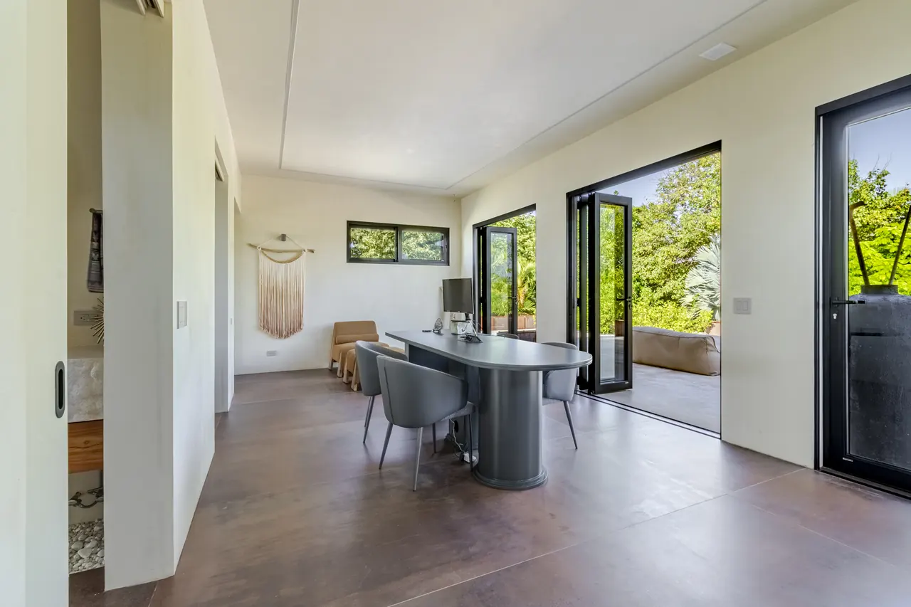 Dedicated workspace with a dark desk and doors opening to the terrace